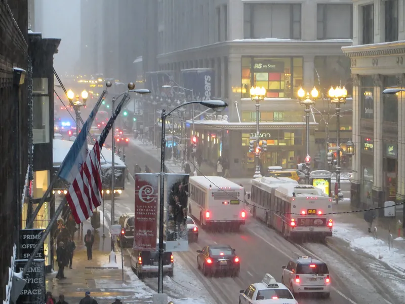 Snowy State Street at Madison with buses and lit storefronts